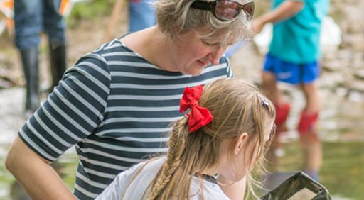 adult and child beside a river looking in a net