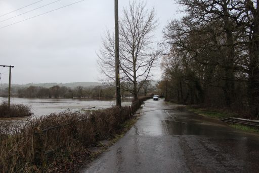 flooded road and field with van in distance