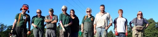A group of volunteers posing with completed willow structure to repair river bank erosion