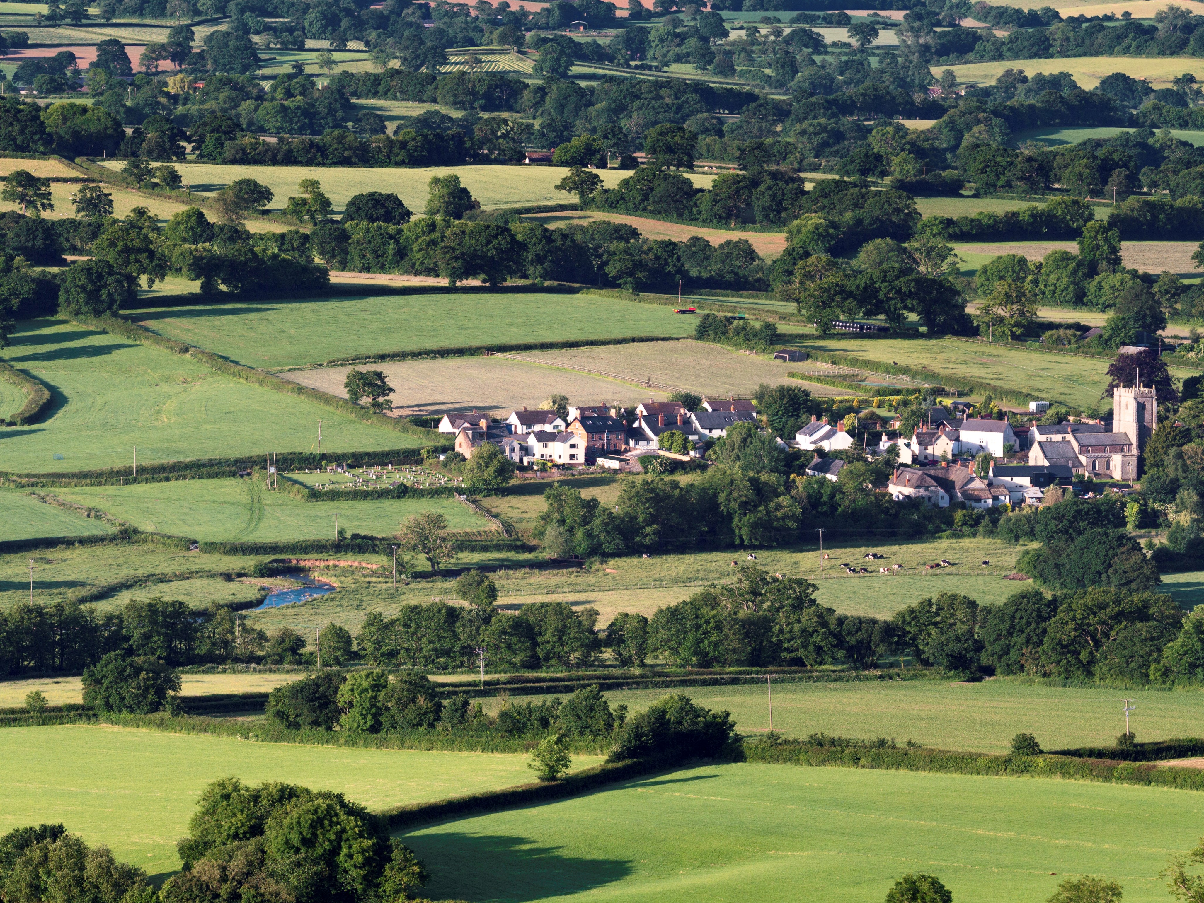 A village set amongst a patchwork of fields and high hedgerows