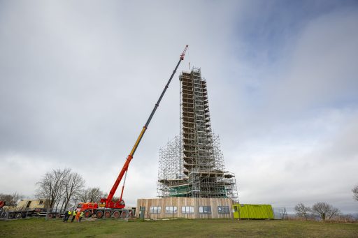 Wellington Monument covered with scaffolding, with a tall crane beside it lifting the large capstone into place