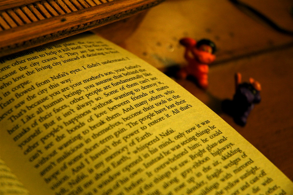 An open book showing text with 2 small toys next to it