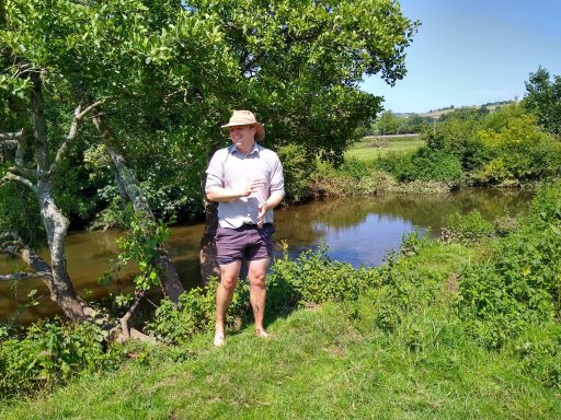 Stephen Johnson standing by the river on a sunny day with bare feet