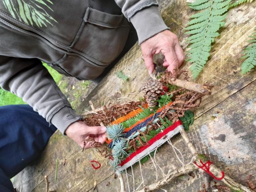 a person wearing a khaki jumper making a nature loom