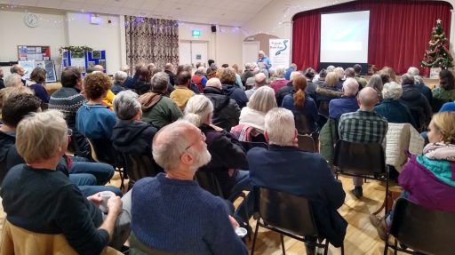 A group of people in Chardstock Village Hall watching a talk