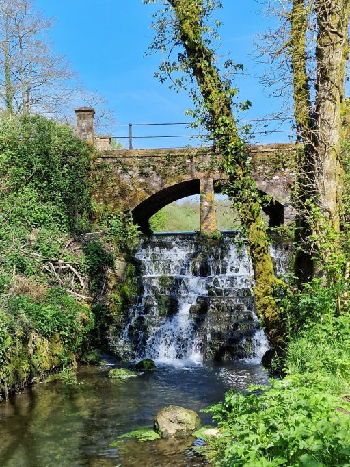 Water cascading down a small waterfall under a stone bridge